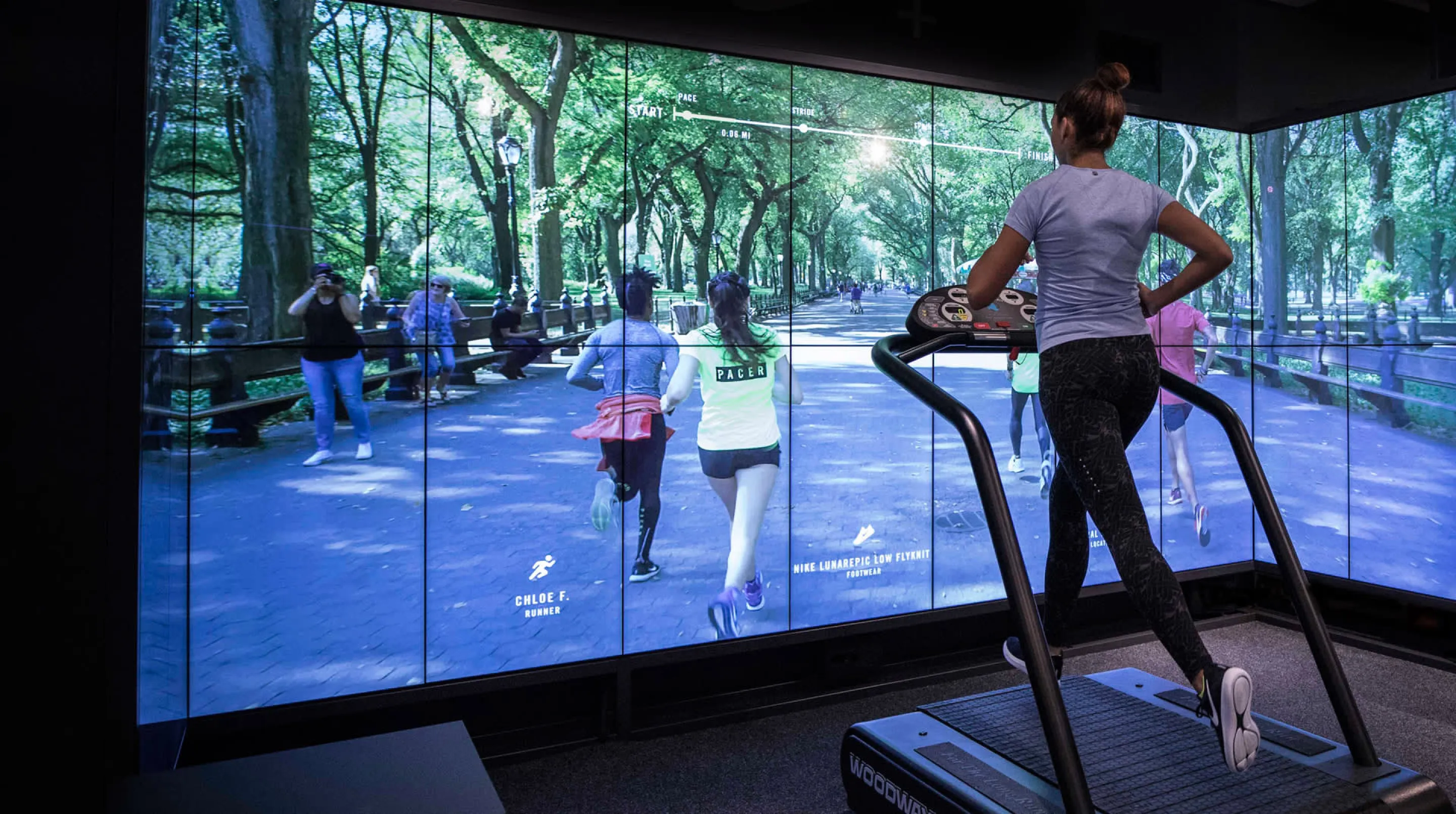 An athlete running on a treadmill in the Trial Zone Experience at the Nike Soho Store in front of the wall-sized screen