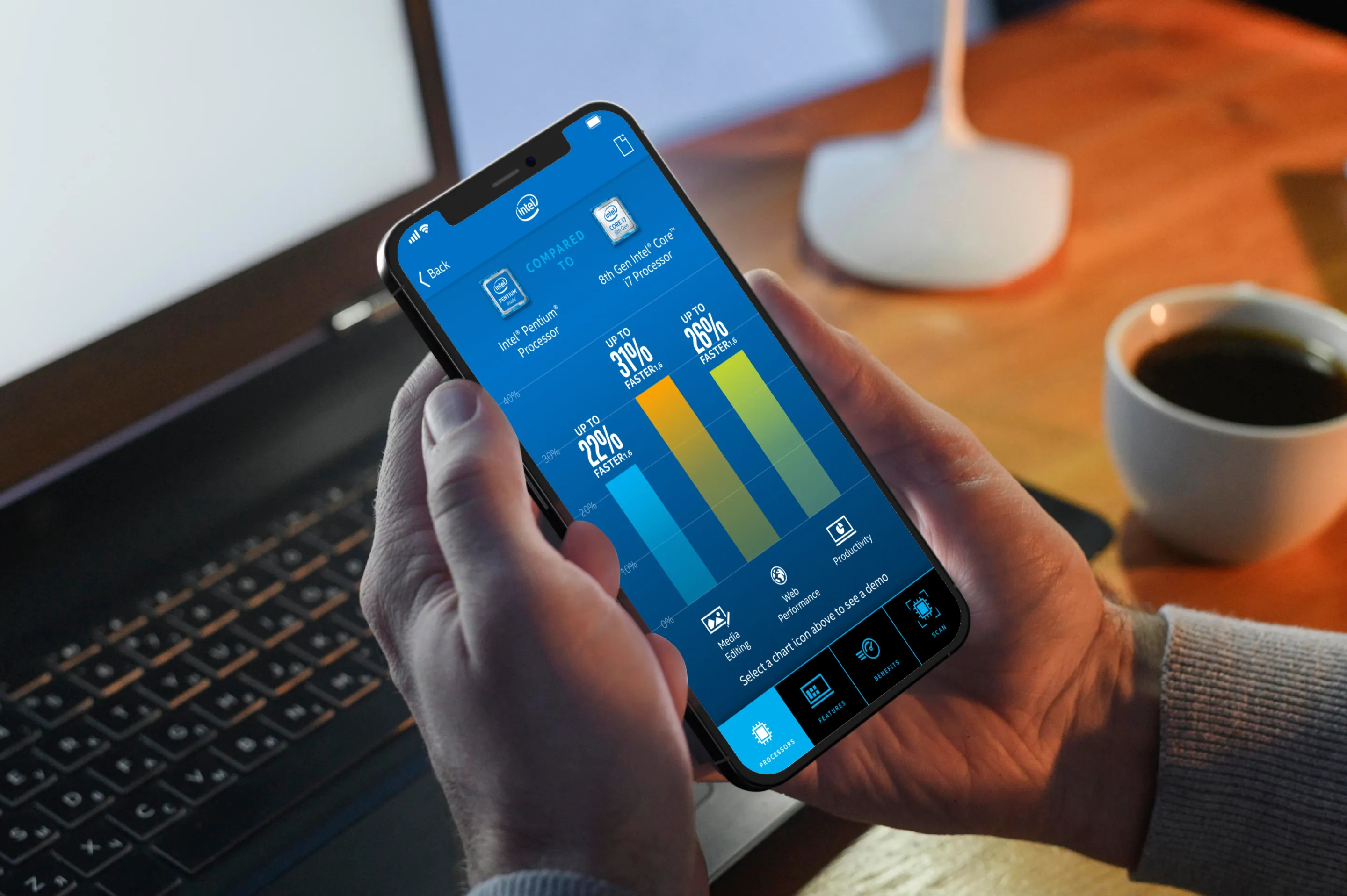 A person holding a phone in front of a computer showing a screen of charts comparing Intel processors for the Intel RXT iOS App with OCR Badge Scanning capability developed by Everyday Odyssey for R/West